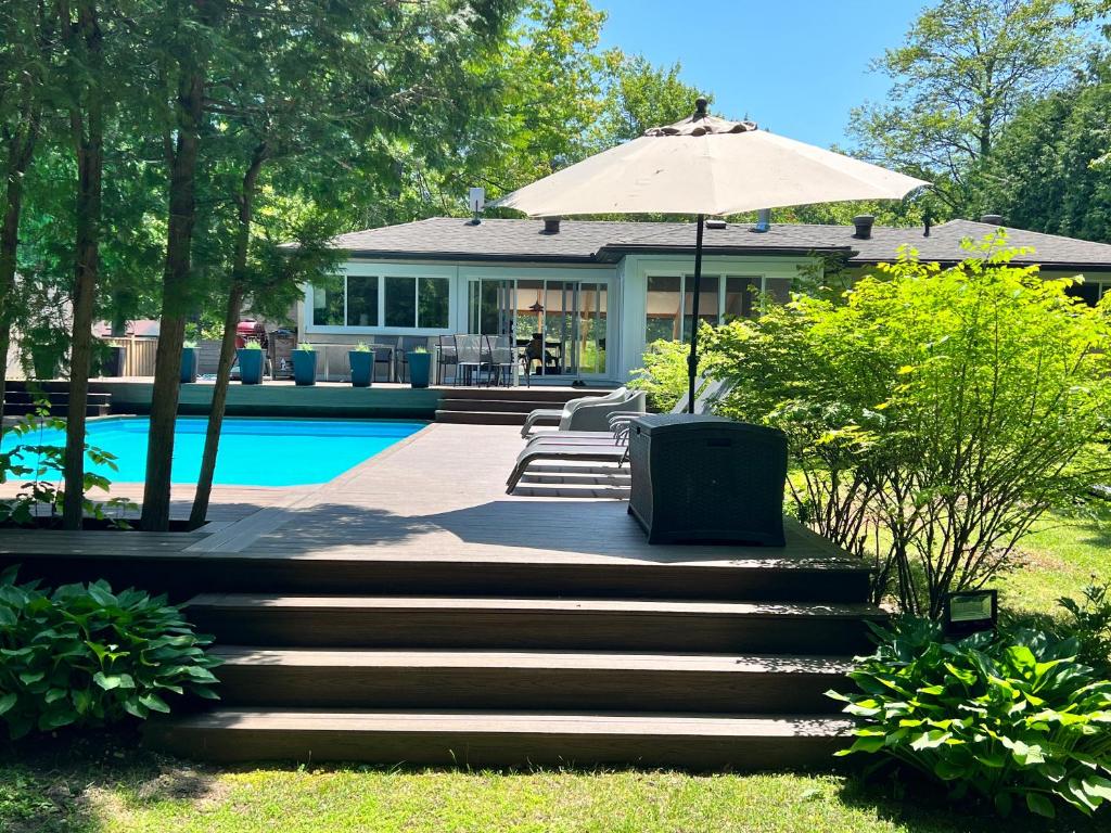 une maison avec une piscine et un parasol dans l'établissement Stunning Modern Beach House with Swimming Pool and Spectacular Sunsets, à Wymbolwood Beach