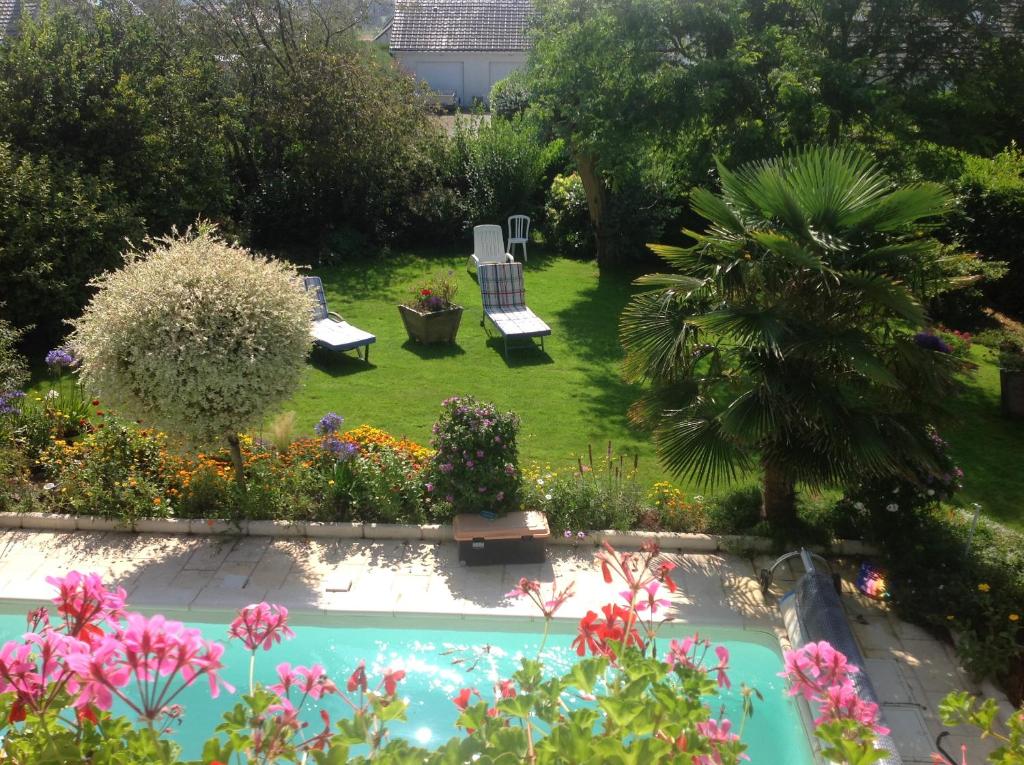 un jardin avec une piscine entourée de chaises et de fleurs dans l'établissement La Maison Bleue Normande, à Étretat
