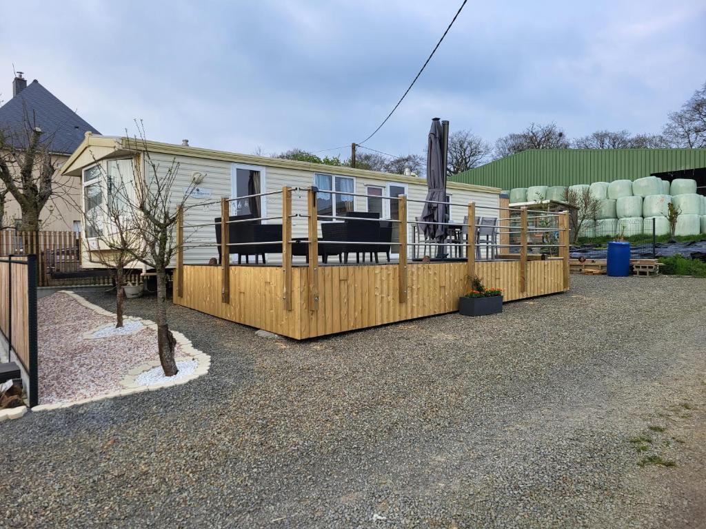 ein Haus mit einem Holzzaun und einer Terrasse in der Unterkunft Mobil Home à la ferme in Le Neufbourg