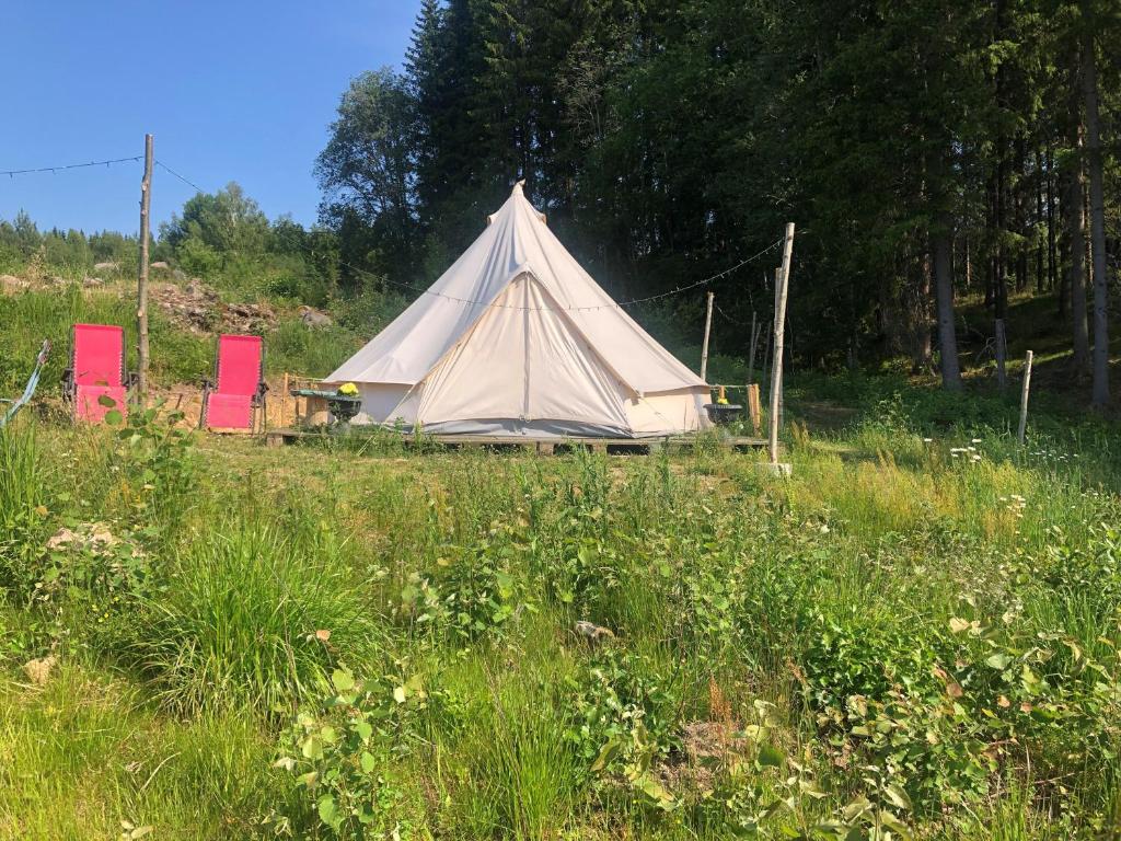 une tente et des chaises blanches dans un champ dans l'établissement Glampingtält, à Torsby