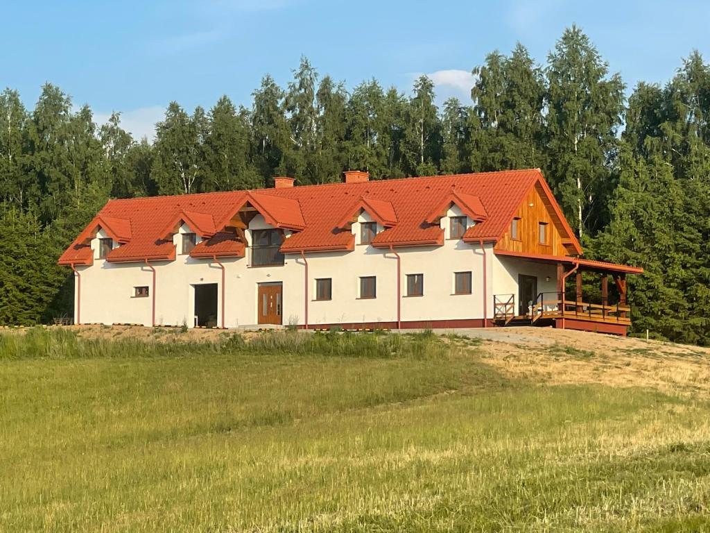 una gran casa blanca con techo naranja en un campo en Siedlisko Czarny Orzeł, en Gawliki Wielkie