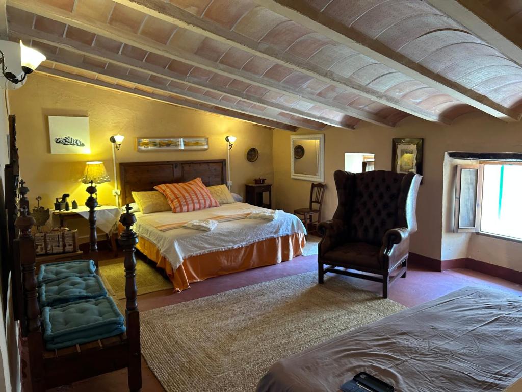 a bedroom with two beds and a chair at Casa Padrina Burballa in Maria de la Salut