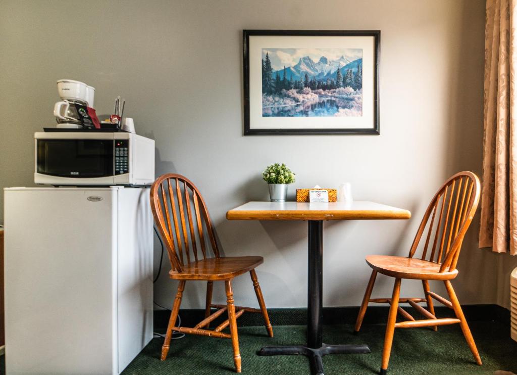 a kitchen with a table and two chairs and a microwave at Mountain View Inn in Canmore