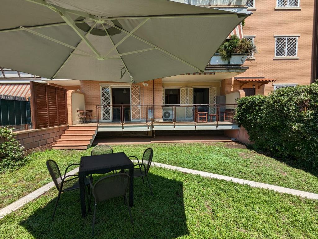 un patio con mesa, sillas y sombrilla en Residenza Alabama, en Roma