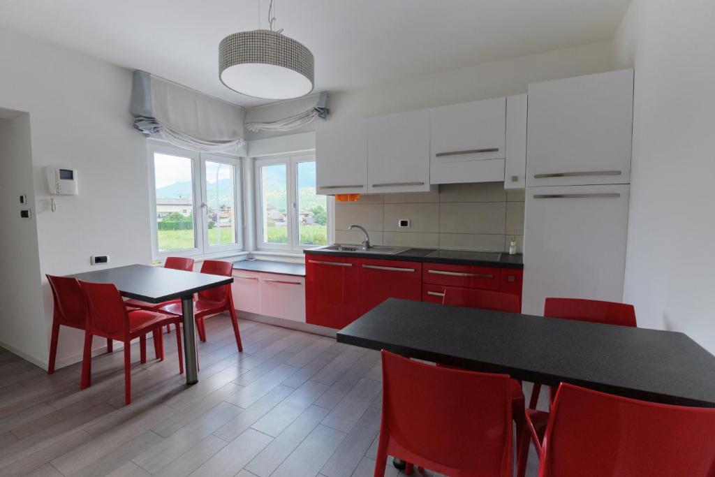 a kitchen with red chairs and a black table at B&B DIVINO in Calceranica al Lago