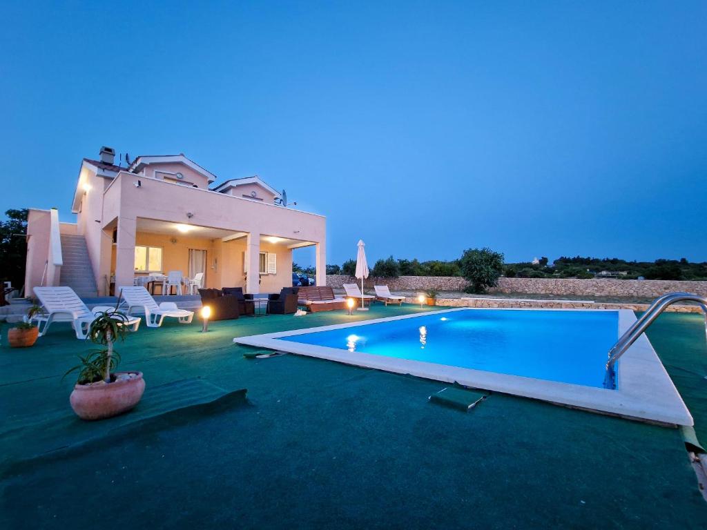 a villa with a swimming pool at night at Vila Cicovac in Novalja