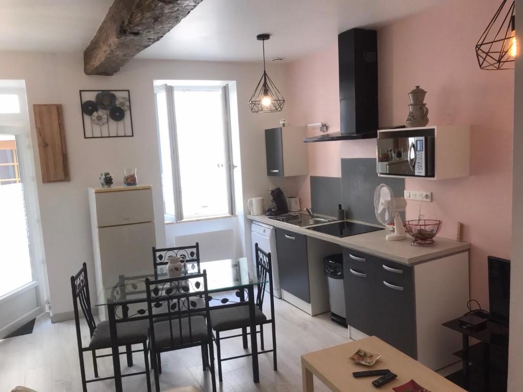 eine Küche mit einem Tisch und Stühlen sowie eine Küche mit einem Waschbecken in der Unterkunft Maison chaleureuse au centre ville in Nérac