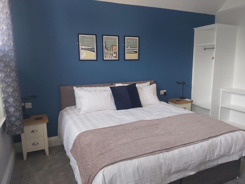 a blue bedroom with a large bed with blue walls at Bay House in Totland