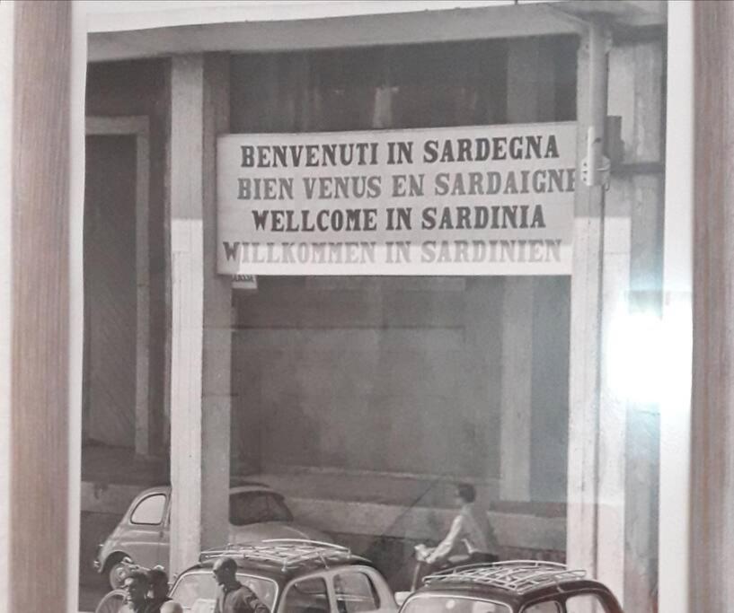 une photo en noir et blanc d'un bâtiment avec un panneau dans l'établissement OLdBIA, à Olbia