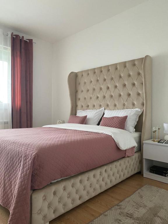 Veternik的住宿－Lilien apartman，一间卧室配有一张大床和粉红色的床罩