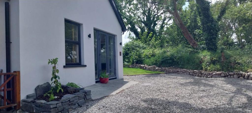 a white house with a door and a yard at The Stables in Skibbereen