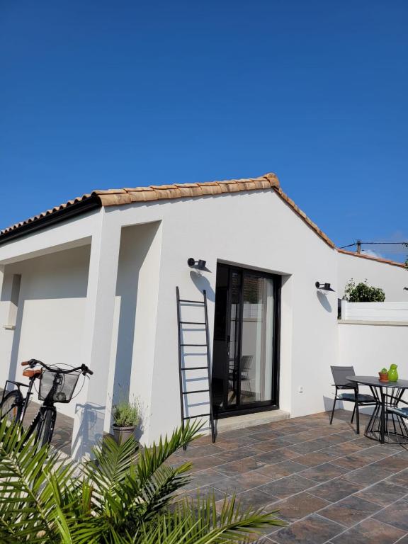 Cette maison blanche dispose d'une terrasse, d'une table et de chaises. dans l'établissement Air marin, à La Bernerie-en-Retz