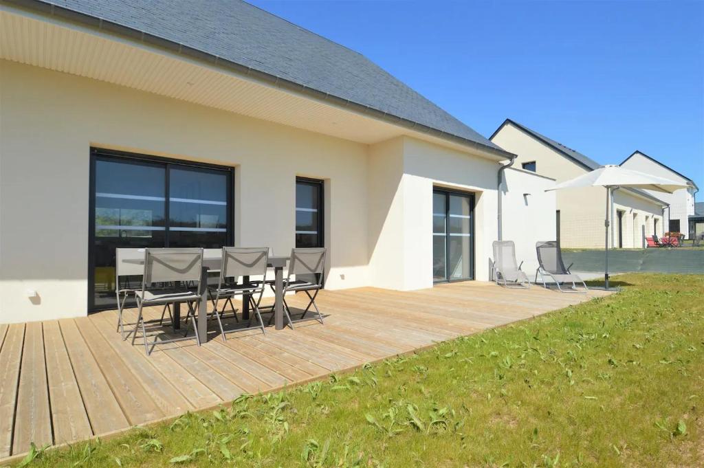 drewniany taras z krzesłami i stół na domu w obiekcie Saint Côme Beach House w mieście Saint-Côme-de-Fresné