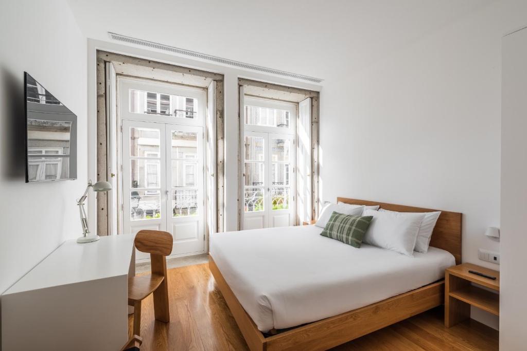 1 dormitorio con 1 cama, escritorio y 2 ventanas en Avenida Viana Boutique Suites, en Viana do Castelo