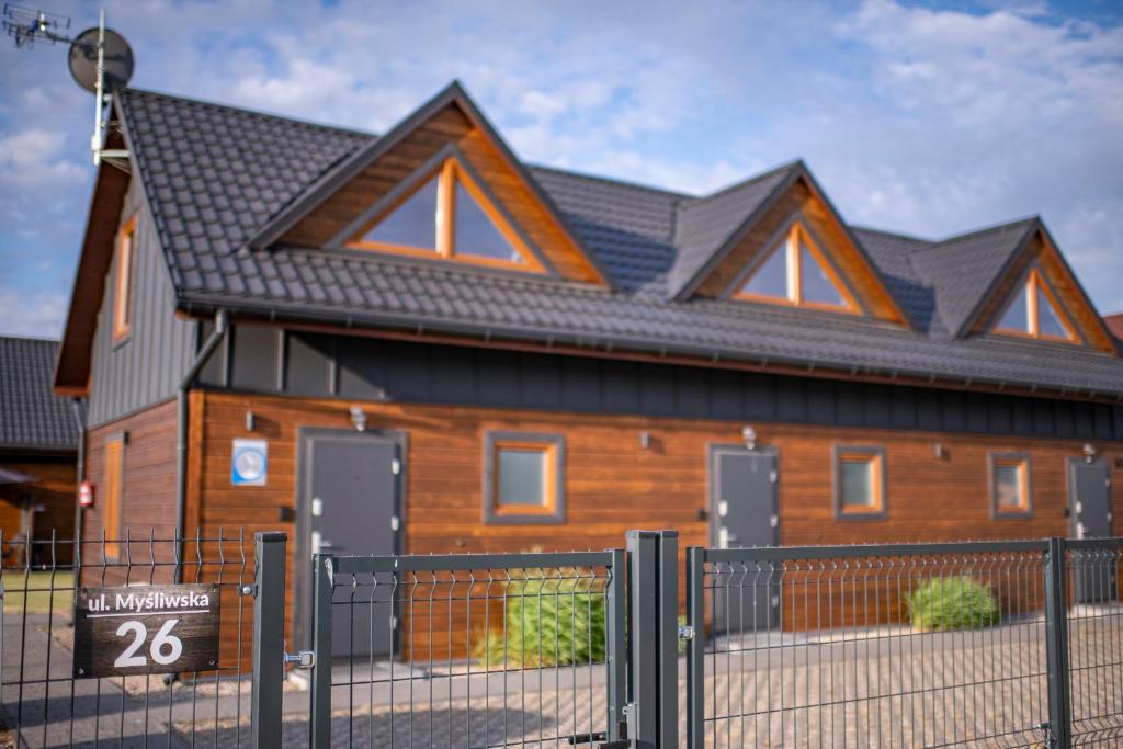 a house with a fence in front of it at Domki przy Mysliwskiej in Grzybowo