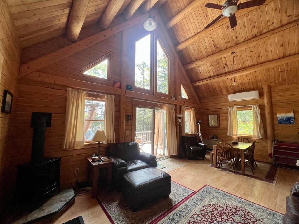 uma sala de estar com paredes de madeira e um tecto com janelas em Beddington Lake Log Cabin 