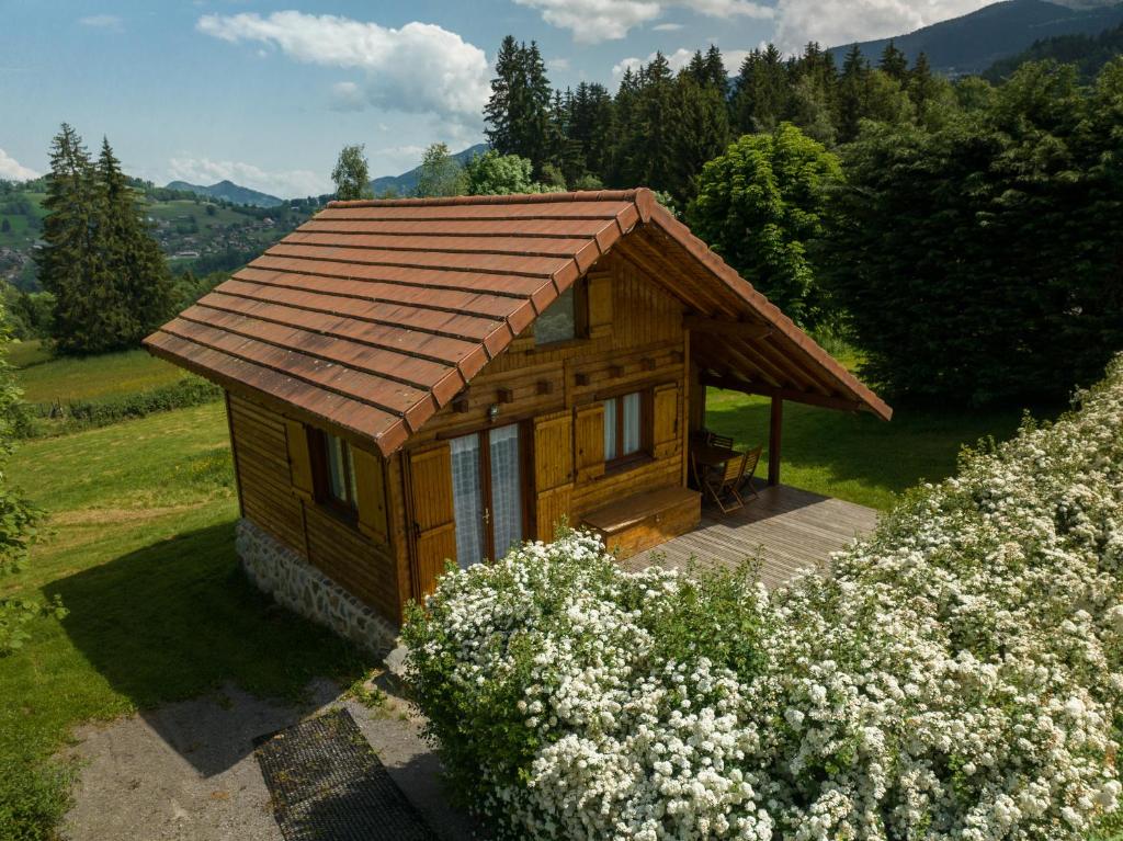 a small wooden cabin in a field with flowers at Chalet individuel à proximité de la station Les 7 Laux in Les Adrets