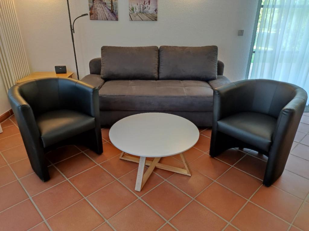 DewichowにあるFerienwohnung Seeterrassenのリビングルーム(ソファ、椅子2脚、テーブル付)