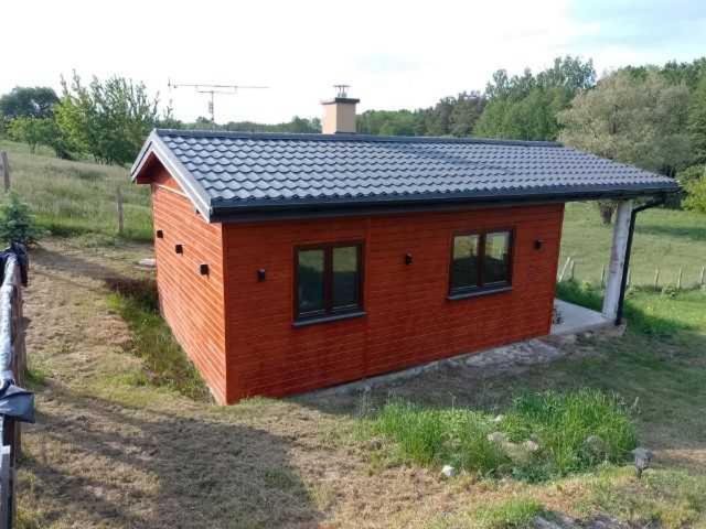 una pequeña casa roja con techo negro en Wakacyjny Apartament - Łaś Ogrody, en Rzewnie