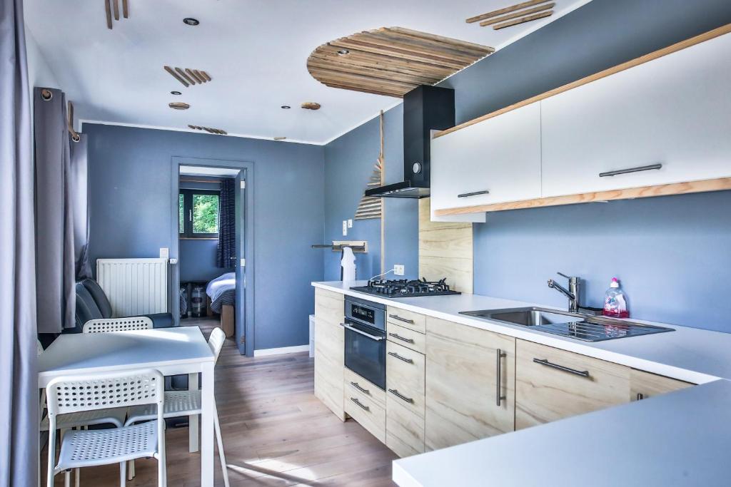 a kitchen with blue walls and wooden cabinets at Tinyhouses - Domain "La vallée des Prés" in Bande