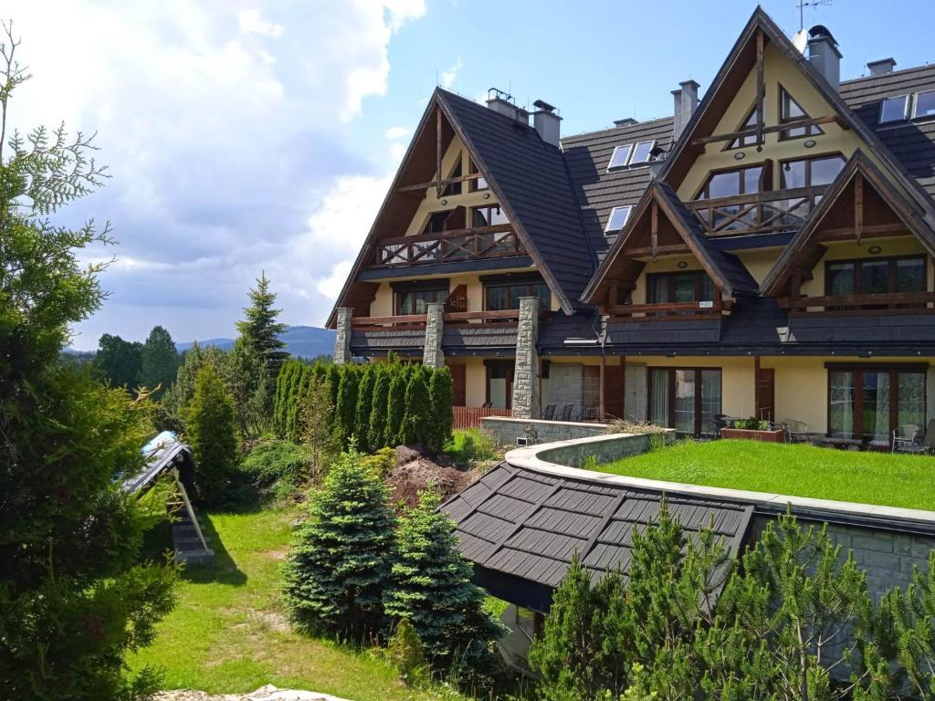 una grande casa in legno con tetto a gambero di Apartament z basenem a Kościelisko