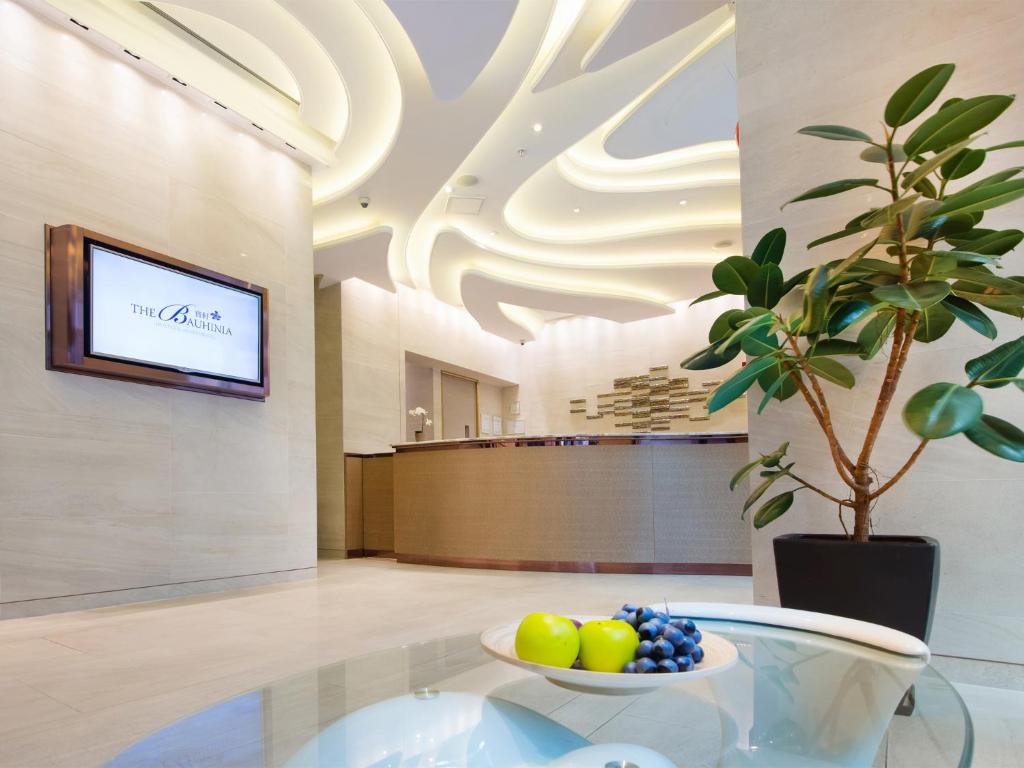 a lobby with a bowl of fruit on a glass table at The Bauhinia Hotel - Tsim Sha Tsui in Hong Kong
