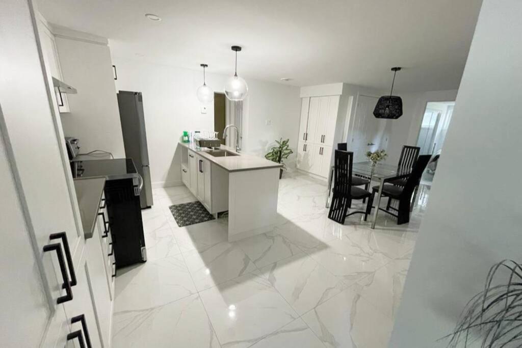 a white kitchen with a sink and a counter at Stylish and luxurious apartment basement unit in Longueuil
