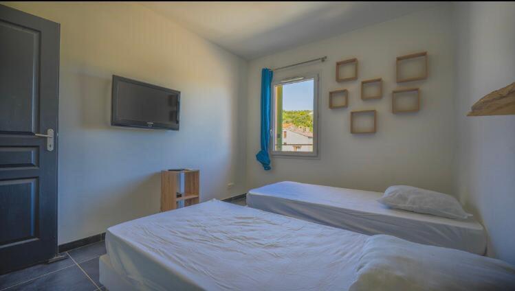 a bedroom with two beds and a tv and a window at Chez Pasqua ! Appartement spacieux avec terrasse 2 chambres 6 couchages en Rooftop in LʼÎle-Rousse