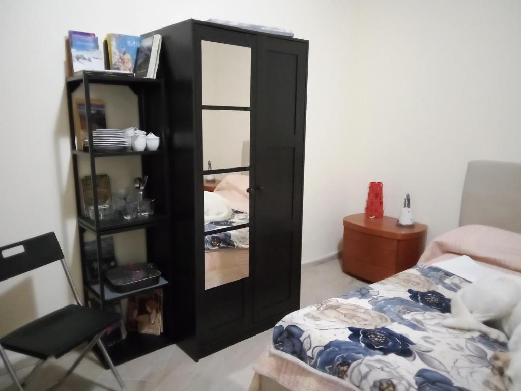 a black cabinet with a mirror next to a bed at Etna Hiking House in Nicolosi