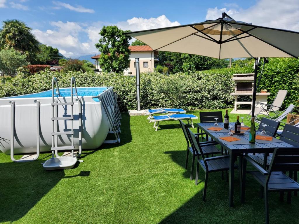 een patio met tafels, een parasol en een zwembad bij A Due Passi dal Lago in Colico