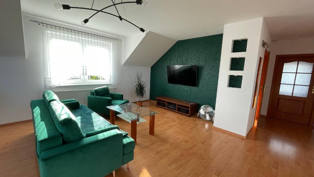 sala de estar con 2 sofás verdes y TV en Apartament Milena, en Władysławowo