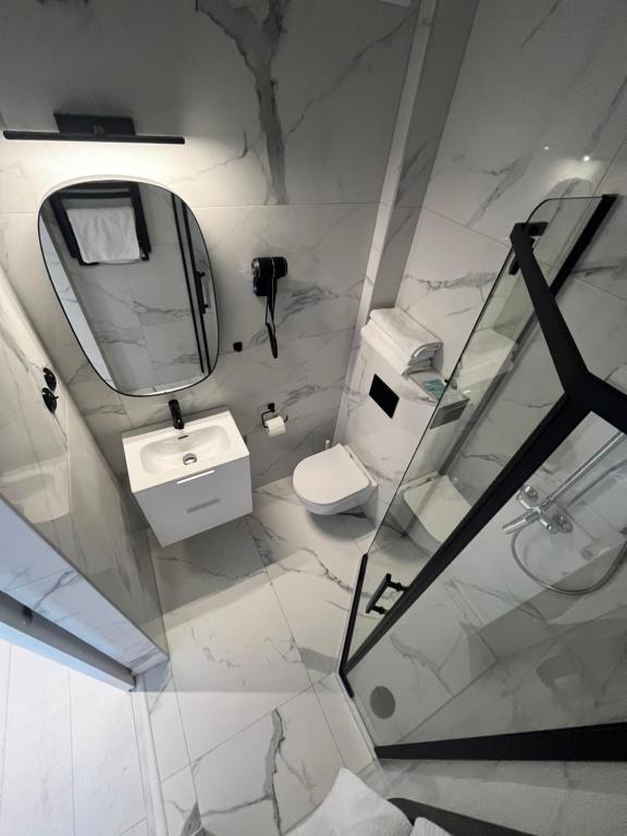 a white bathroom with a sink and a mirror at Pod Różą in Łeba