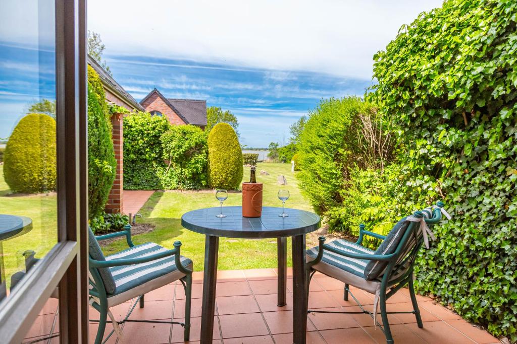 patio con 2 sedie e tavolo con bicchieri da vino di Apartment Biber mit Terrasse a Dewichow