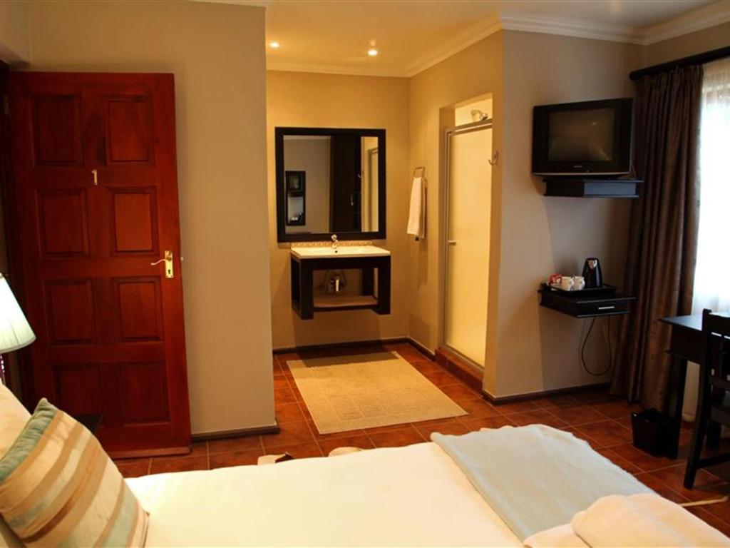 East View Guesthouse في بريتوريا: غرفة بسرير وحمام مع حوض