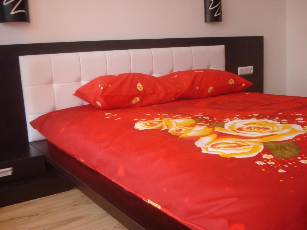 a bed with red sheets and red pillows with roses on it at Apartment Beach View Plaza in Pomorie