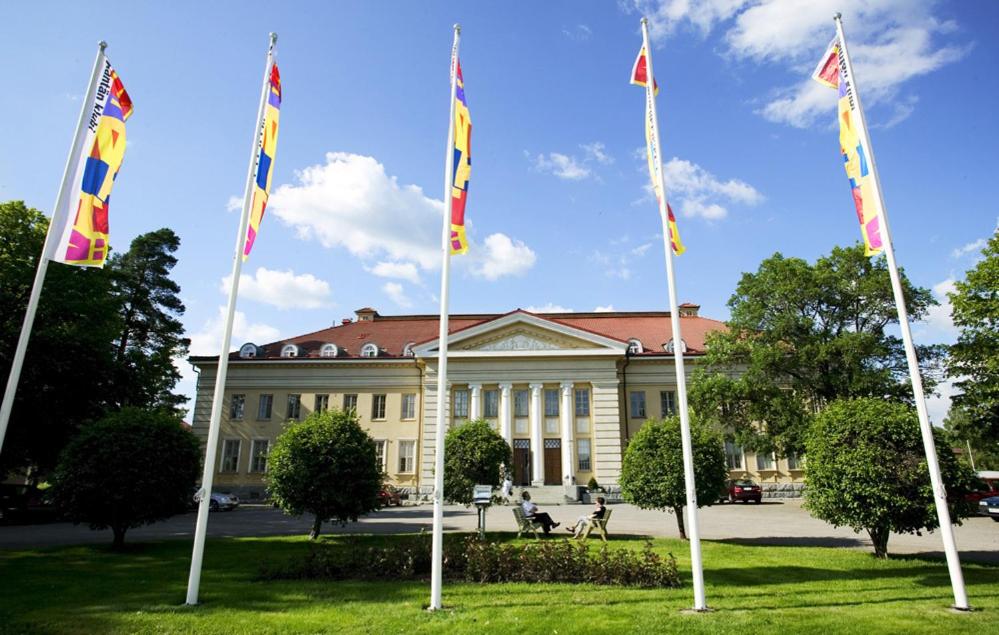 eine Gruppe von Flaggen vor einem Gebäude in der Unterkunft Hotelli-Ravintola Mäntän Klubi in Mänttä