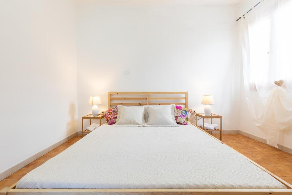 ein Schlafzimmer mit einem großen weißen Bett mit zwei Lampen in der Unterkunft La Casa del Mare - 100mt dalla spiaggia - Lenzuola&Asciugamani in Solanas