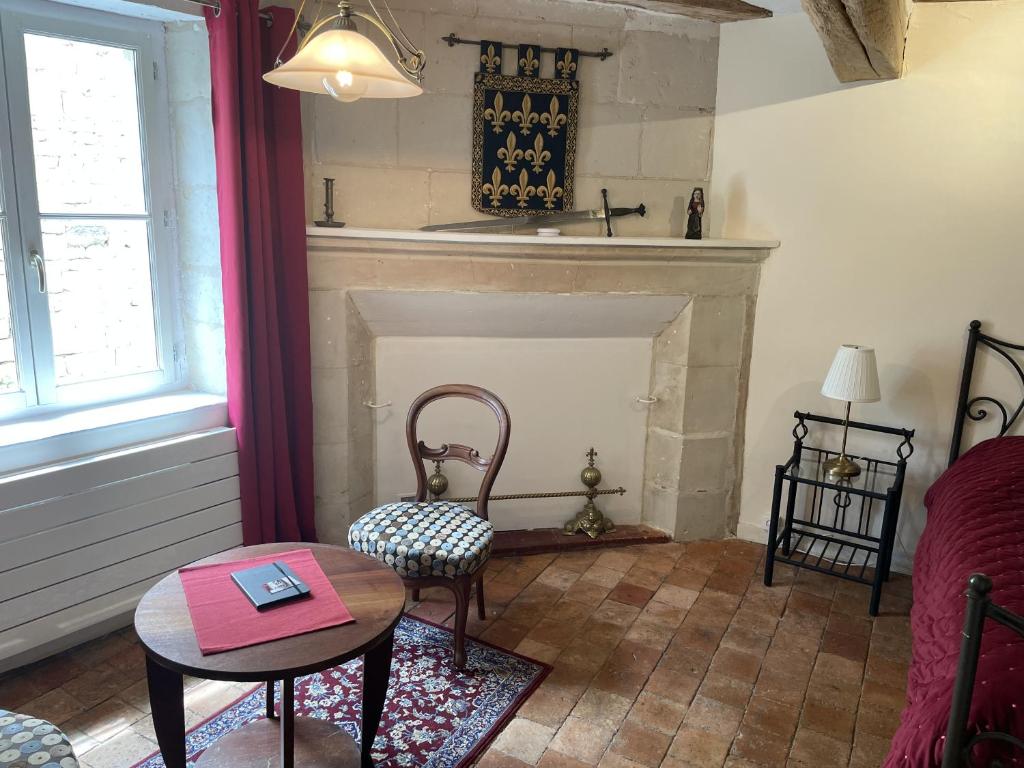 a living room with a fireplace and a table and chairs at Le colombier in Le Coudray-Macouard