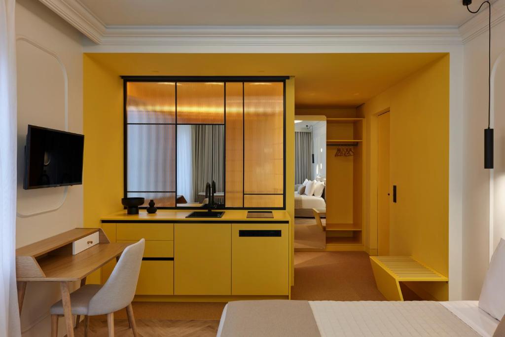 a room with a yellow kitchen with a desk and a television at DWELL - Elegant City Stay in Athens