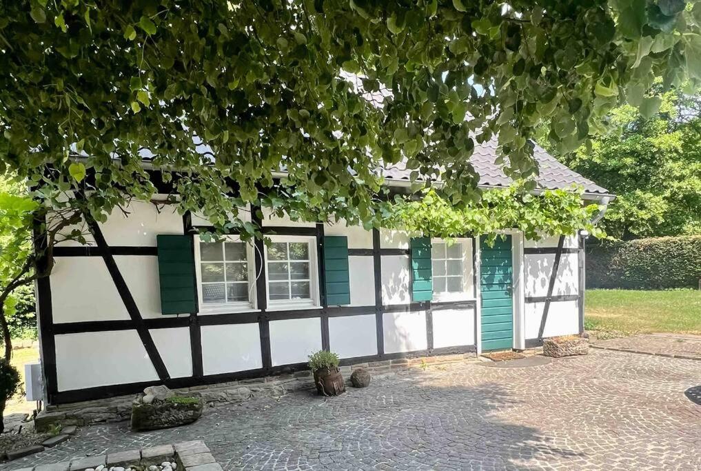 a black and white house with green shutters at Mühlenhaus Herkenrath in Bergisch Gladbach
