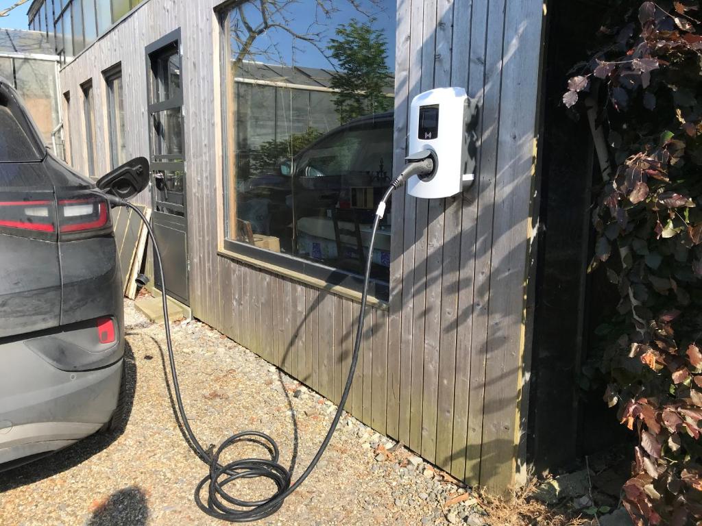 a car plugged into a house with a charging cable at Grysperre B&B in Hooglede