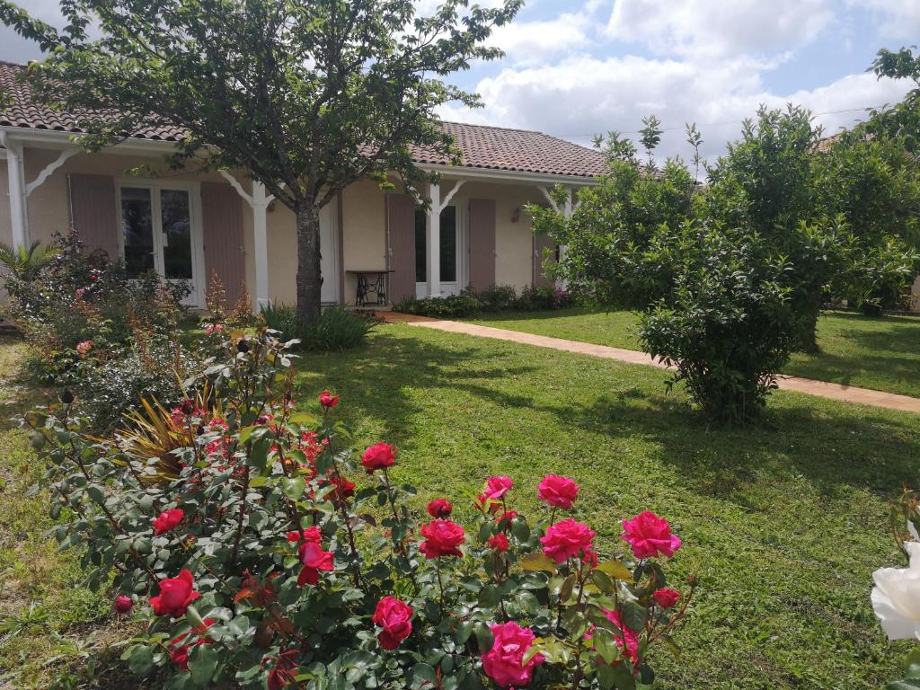 una casa con rosas rojas en el patio en La Roseraie, en Tonneins