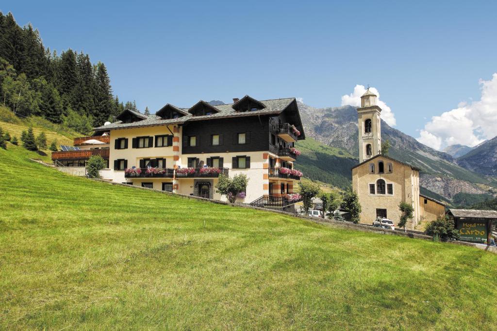 una gran casa en una colina con una iglesia en Hotel Cardo, en Valdidentro