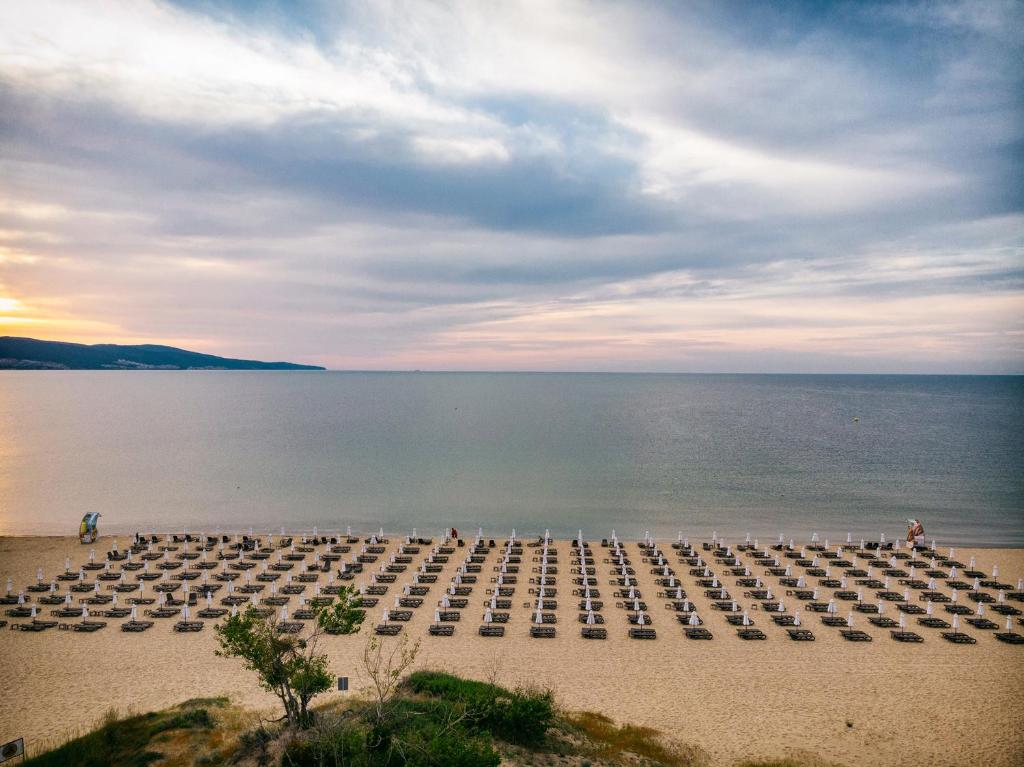 eine große Gruppe von Stühlen am Strand in der Nähe des Wassers in der Unterkunft Viand Hotel - Premium All Inclusive in Sonnenstrand