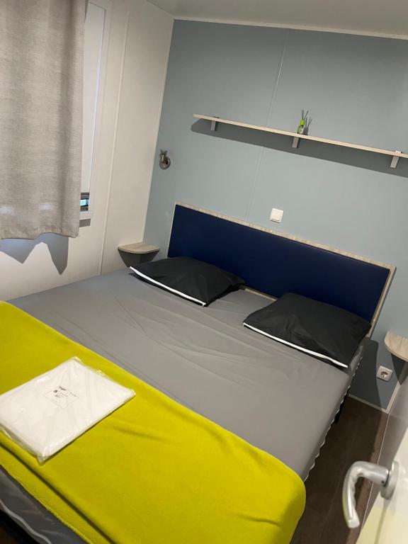 Cama grande en habitación con colchón amarillo en Mobile home camping en Le Grau-du-Roi