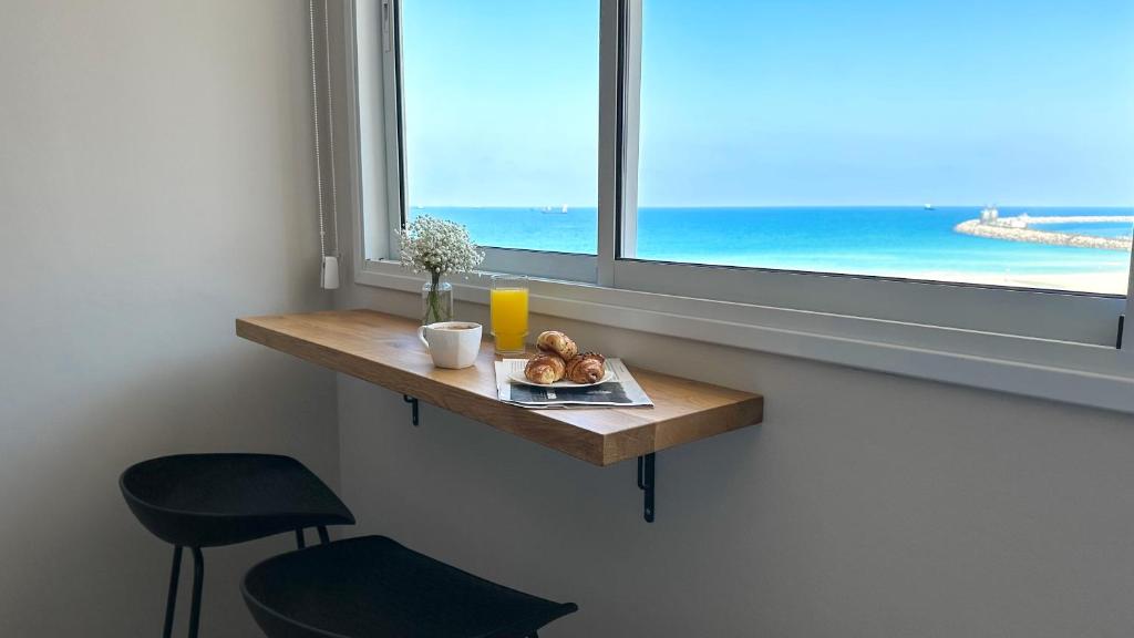 a table with a plate of food on it next to a window at Angel Apt-Amazing SeaView-Netfix-Wifi-Free Parking in Ashdod