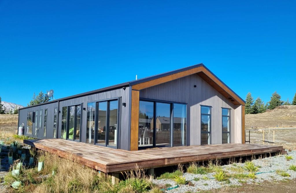 a small house with a wooden deck in a field at Ahuru Mōwai in Lake Tekapo