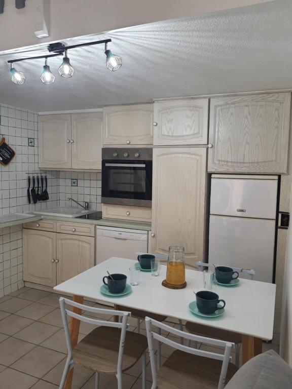 eine Küche mit einem weißen Tisch mit zwei Schüsseln darauf in der Unterkunft A 500 m de la plage, tout confort avec wifi in Le Barcarès