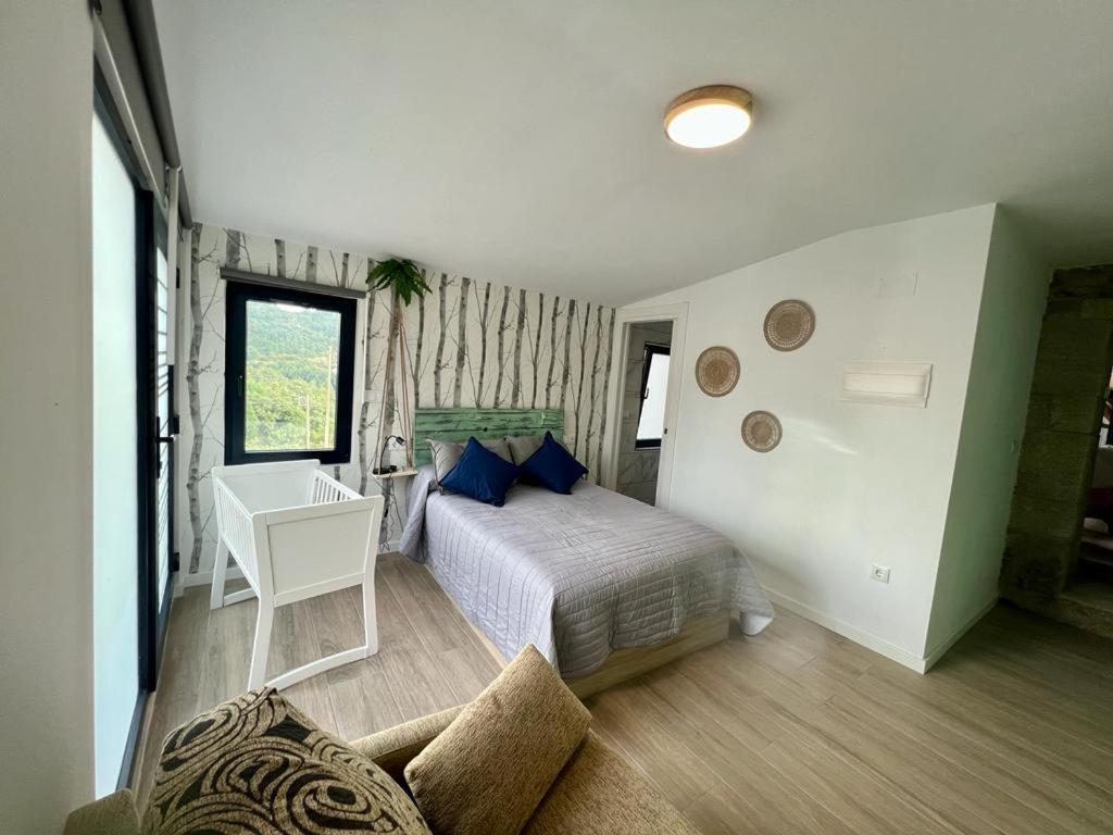 1 dormitorio con cama con almohadas azules y escritorio en O Recuncho de Tibias en Pereiro de Aguiar