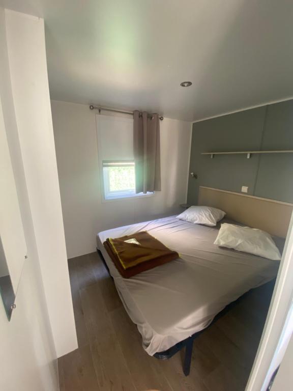 Schlafzimmer mit einem großen Bett und einem Fenster in der Unterkunft Mobil Home 4 personnes in Narbonne-Plage